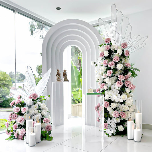 pink and white flower towers with led butterflies next to white 3d arch backdrop