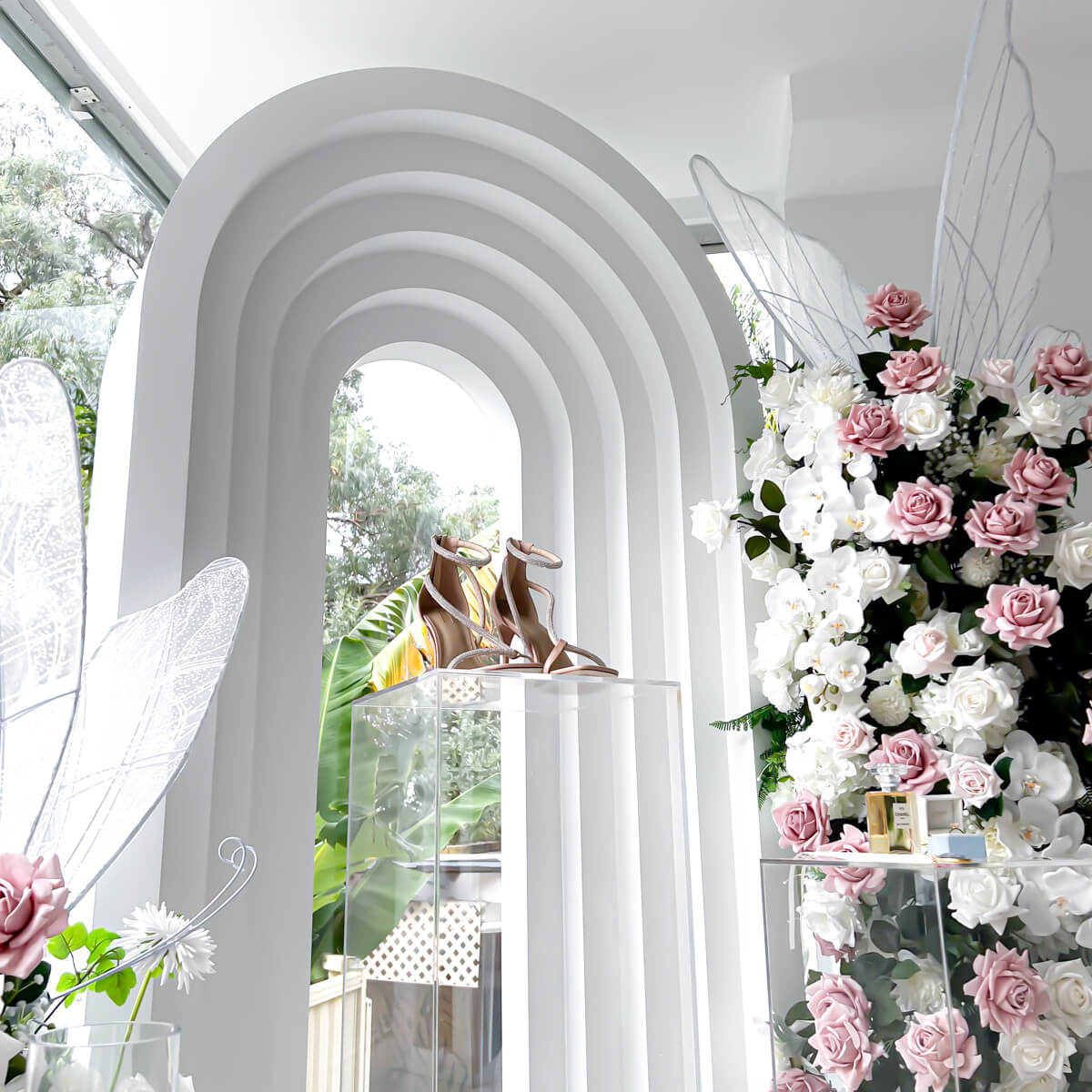 wedding heels on clear plinth in front of white 3d arch backdrop