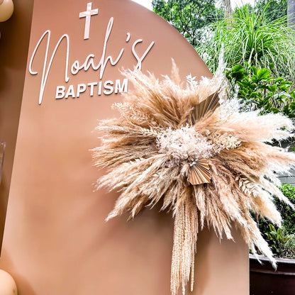 boho flower arrangement attached to beige backdrop with white acrylic lettering