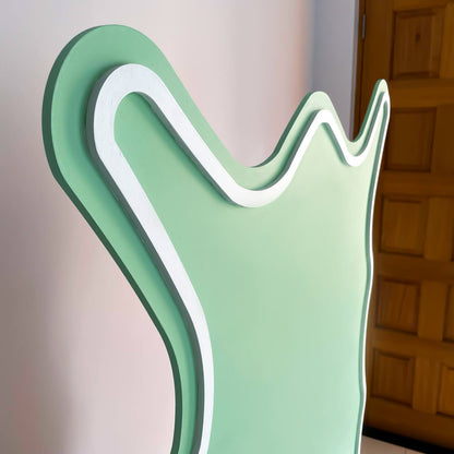 close up image of green curly backdrop board with white trimming standing on floor