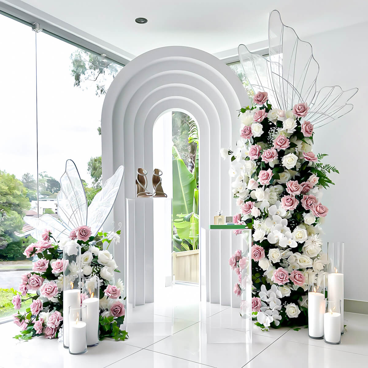 white 3d rainbow arch backdrop with dusty pink and white rose flower arrangement towers and led butterflies