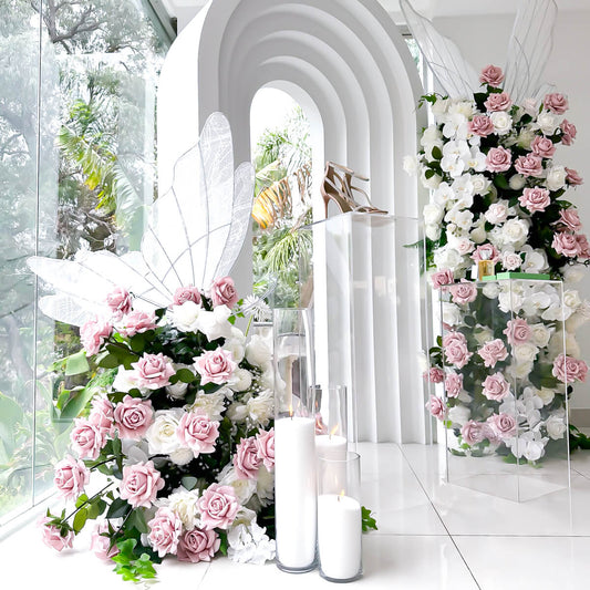 dusty pink and white rose flower arrangements in front of white 3d arch backdrop with white sand candles