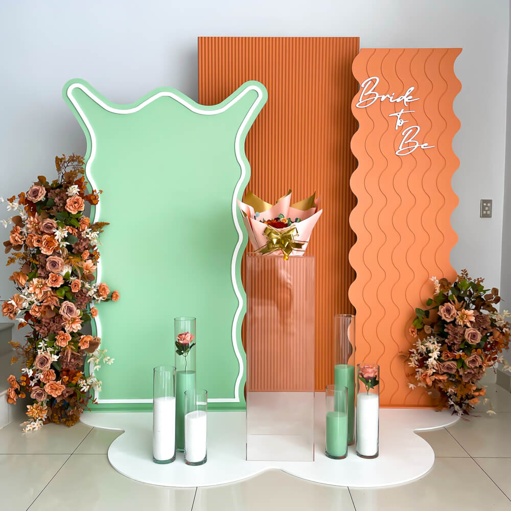 green and white sand candles on white mat in front of orange and green backdrop boards