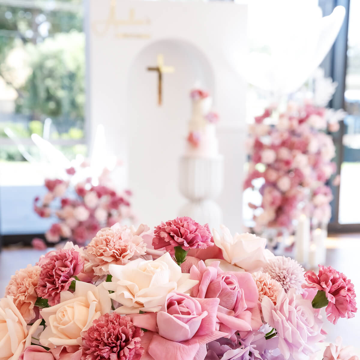 mixed pink flower arrangement with white 3d arch backdrop in background