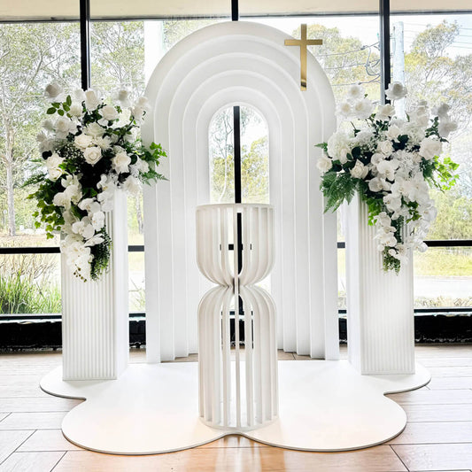 White 3D arch backdrop with green and white florals on plinths