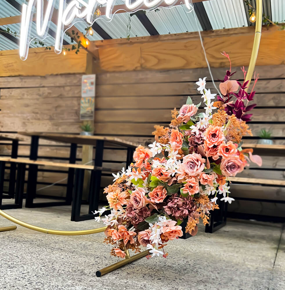 artificial flower arrangement hanging on gold circle hoop backdrop