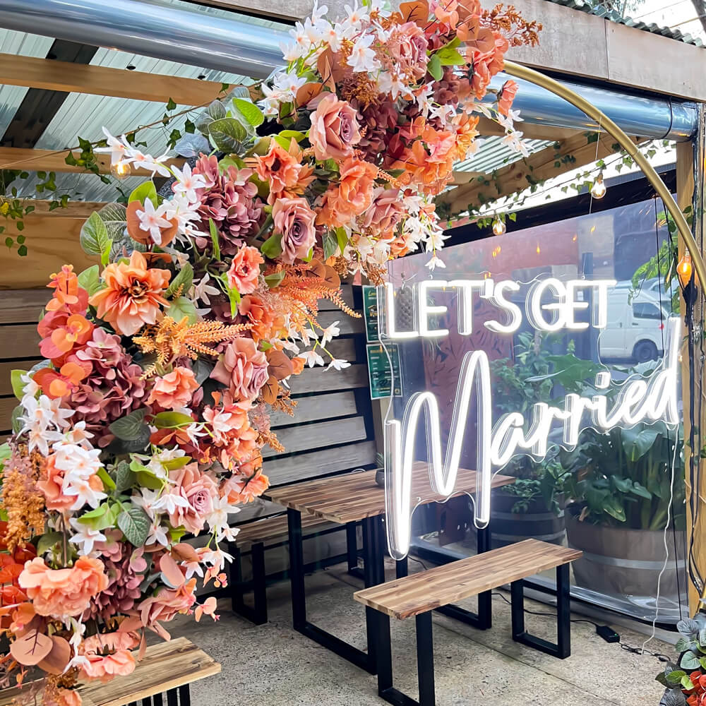 artificial flower arrangement hanging on gold circle hoop backdrop