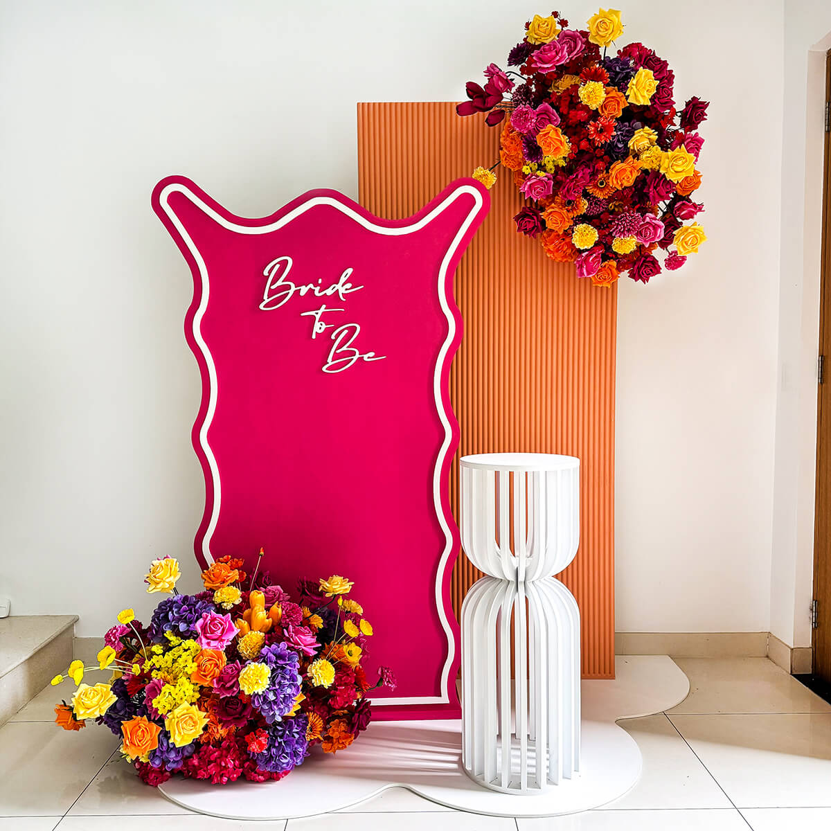 Hot pink and orange backdrop with white plinth and floral arrangements