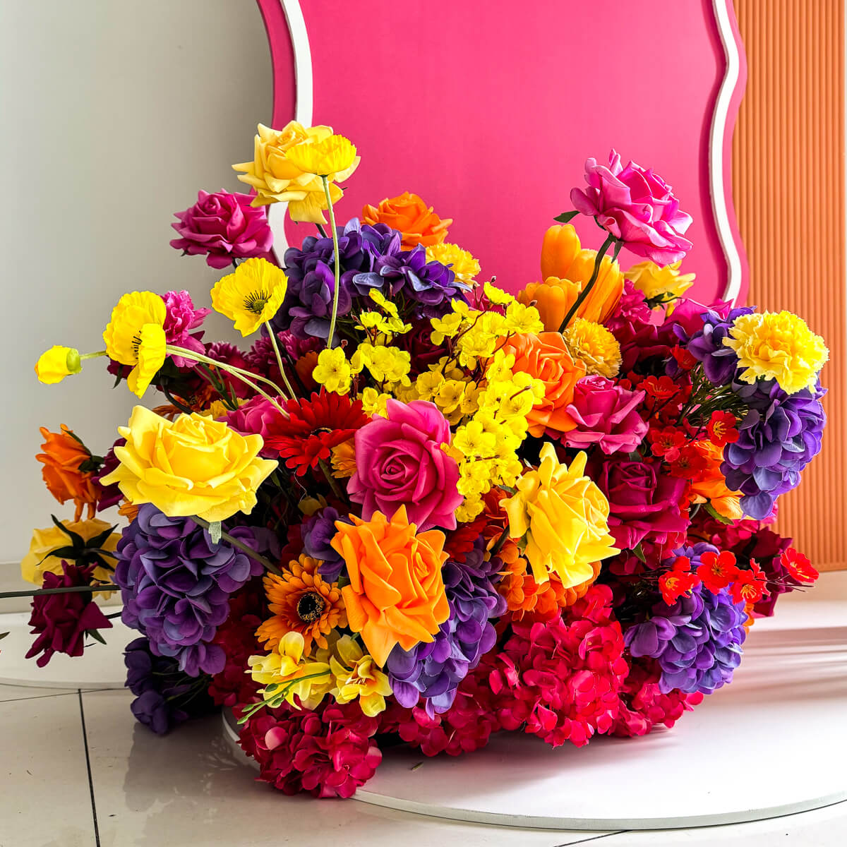 tropical flower arrangement on floor in front of hot pink and orange backdrops