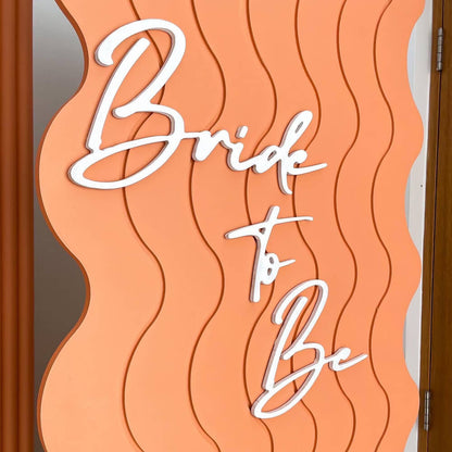 white bride to be lettering stuck on wavy orange backdrop board