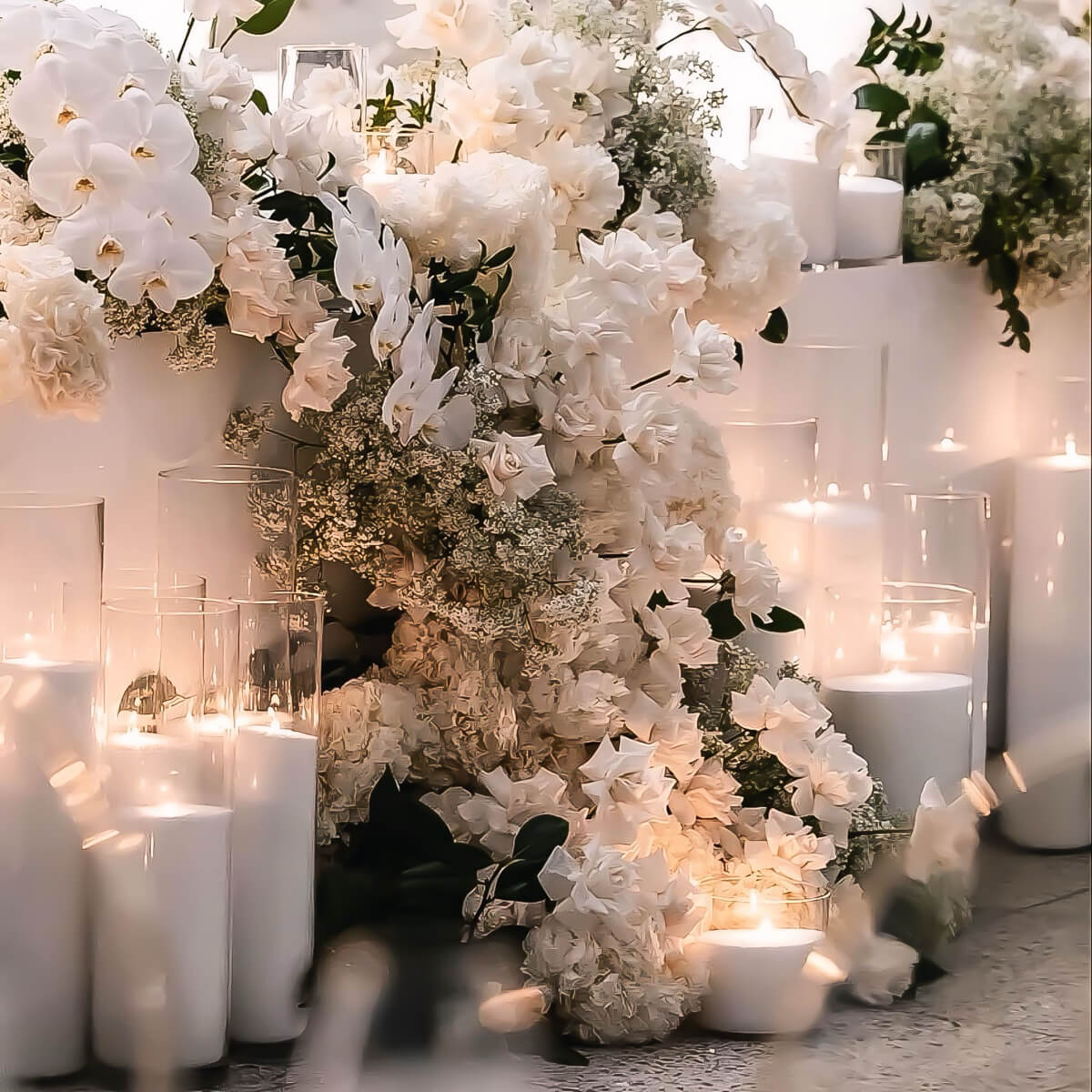 white sand candles on floor in front of bridal table with white roses and baby breath