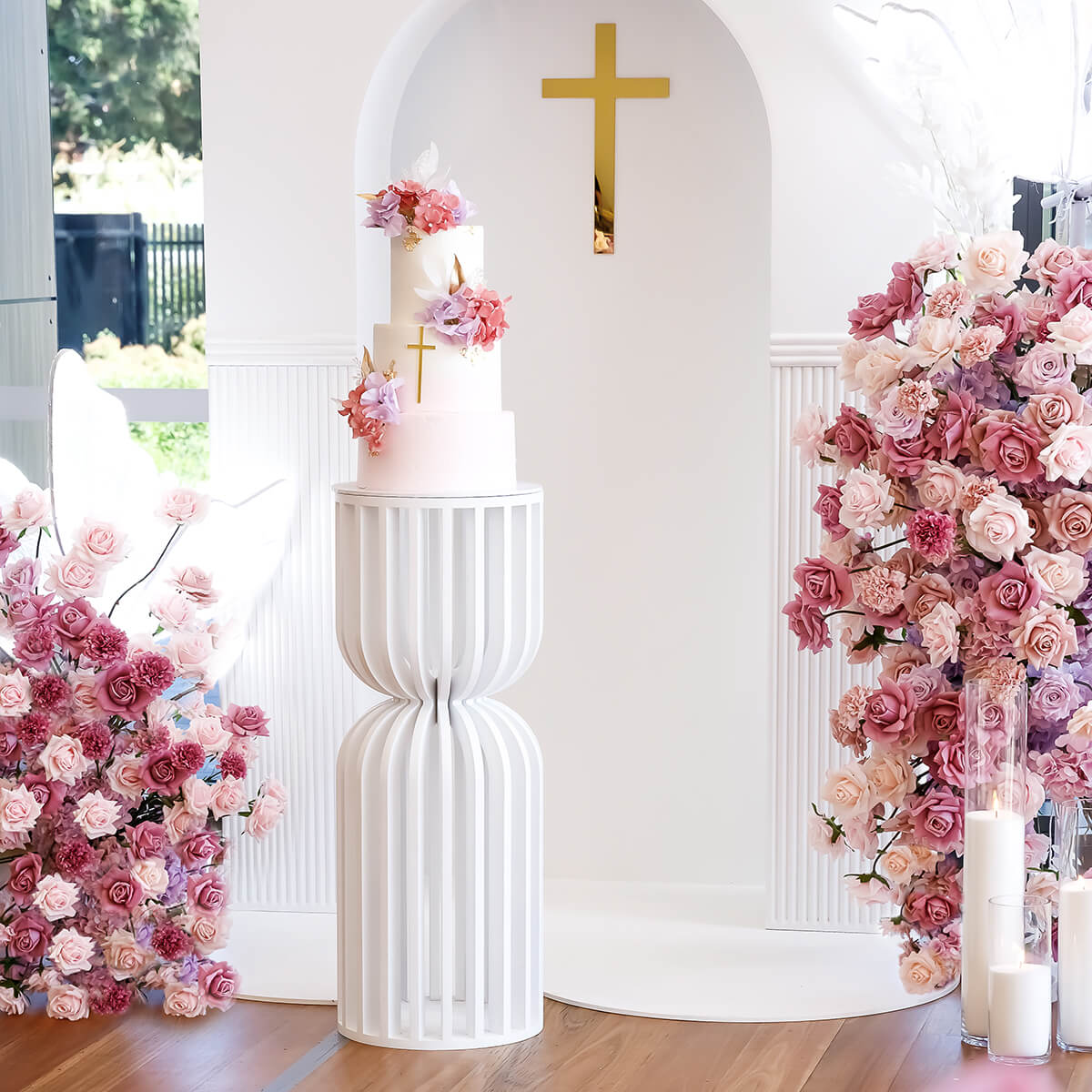 cake placed on white slatted roman plinth with pink and purple rose backdrop