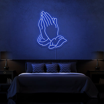 blue praying hands neon sign hanging on bedroom wall