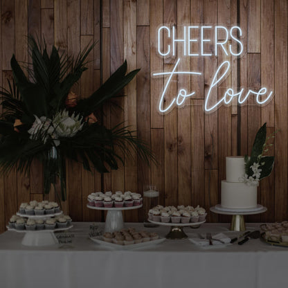 cold white cheers to love neon sign hanging above dessert table