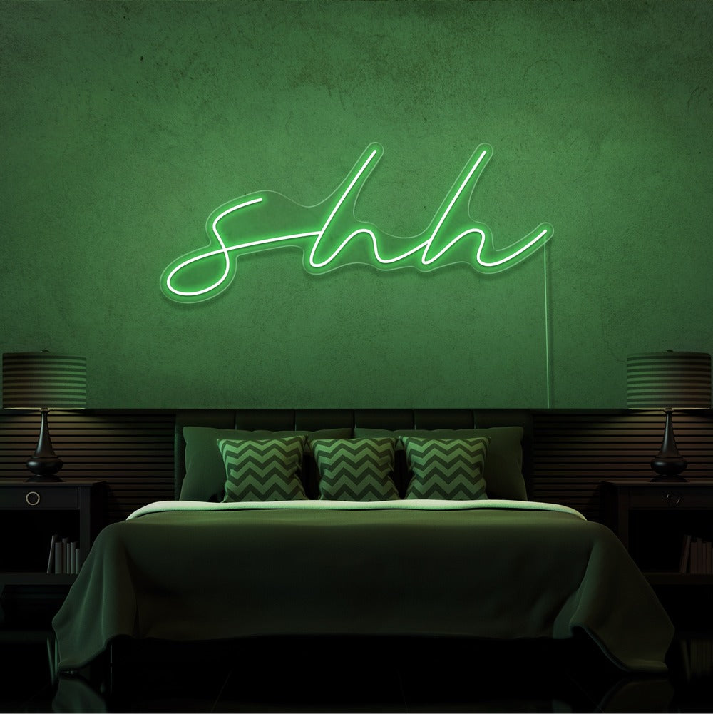 green shh neon sign hanging on bedroom wall