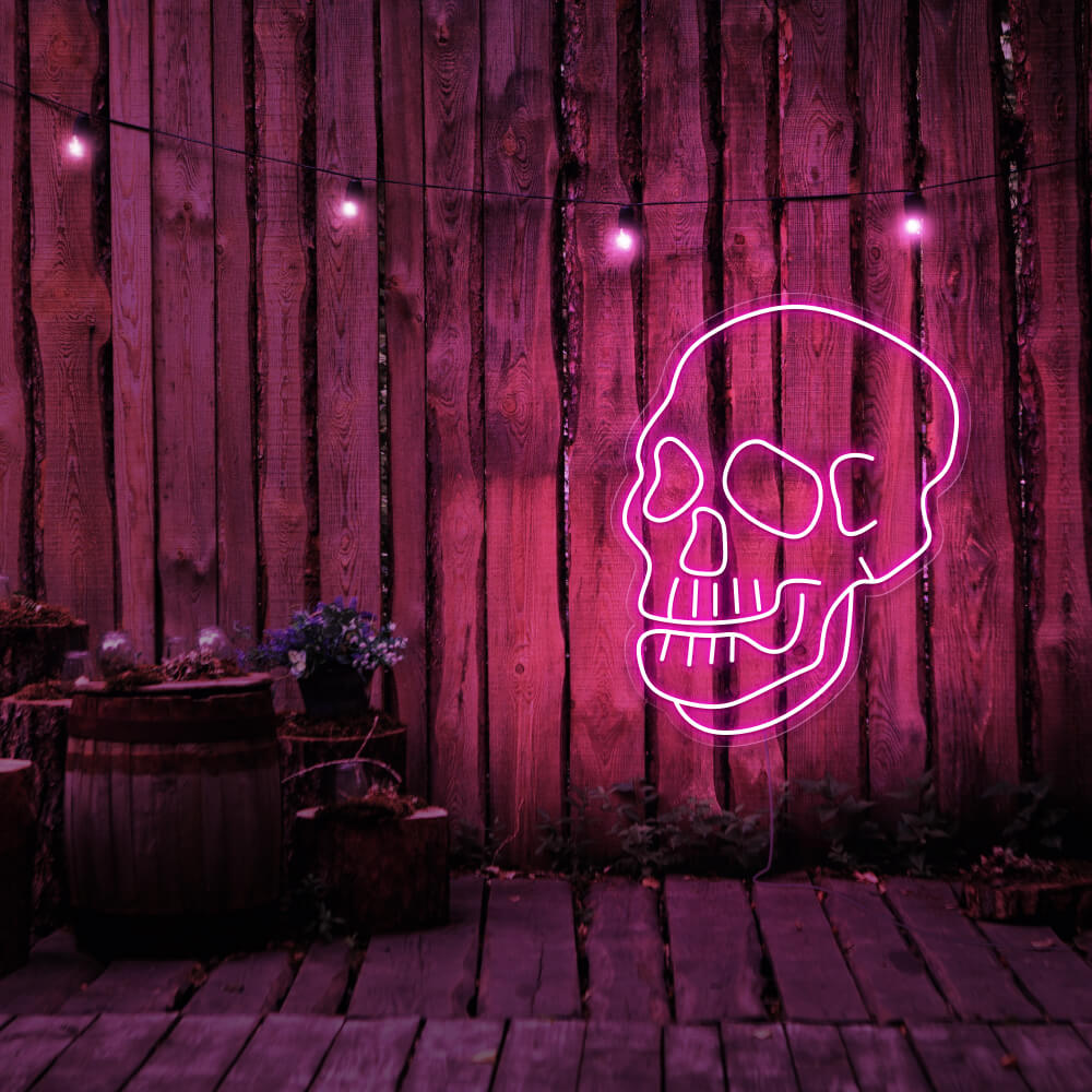 hot pink skull neon sign hanging on timber fence