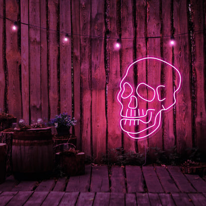 hot pink skull neon sign hanging on timber fence
