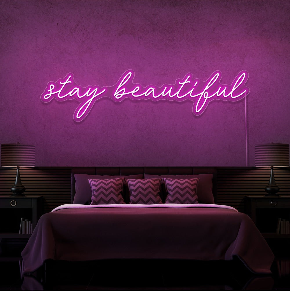 hot pink stay beautiful neon sign hanging on bedroom wall