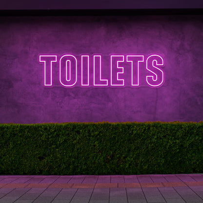 hot pink toilets neon sign hanging on outdoor wall