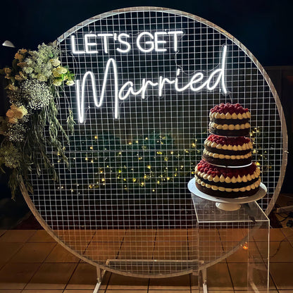 white lets get married neon sign hanging on white mesh backdrop frame
