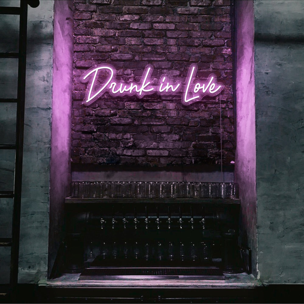 light pink drunk in love neon sign hanging on bar wall