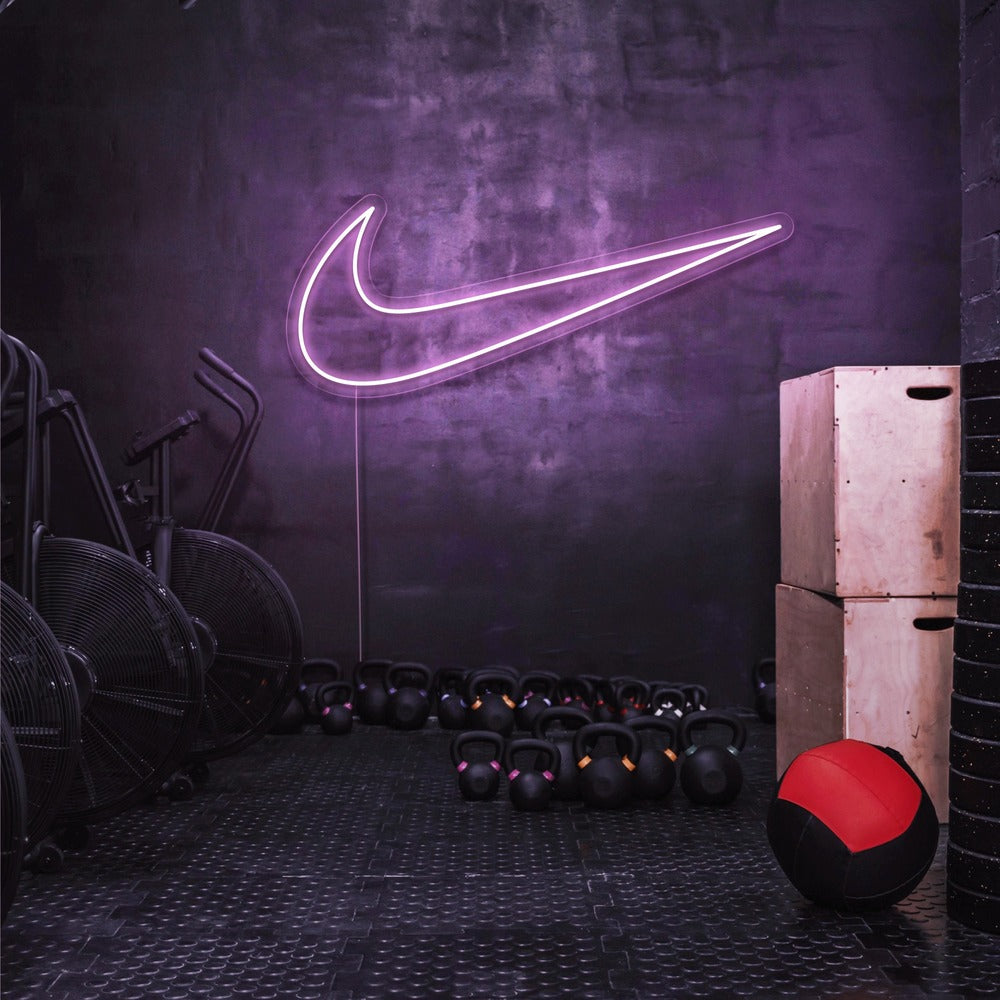 light pink nike swoosh neon sign hanging on gym wall