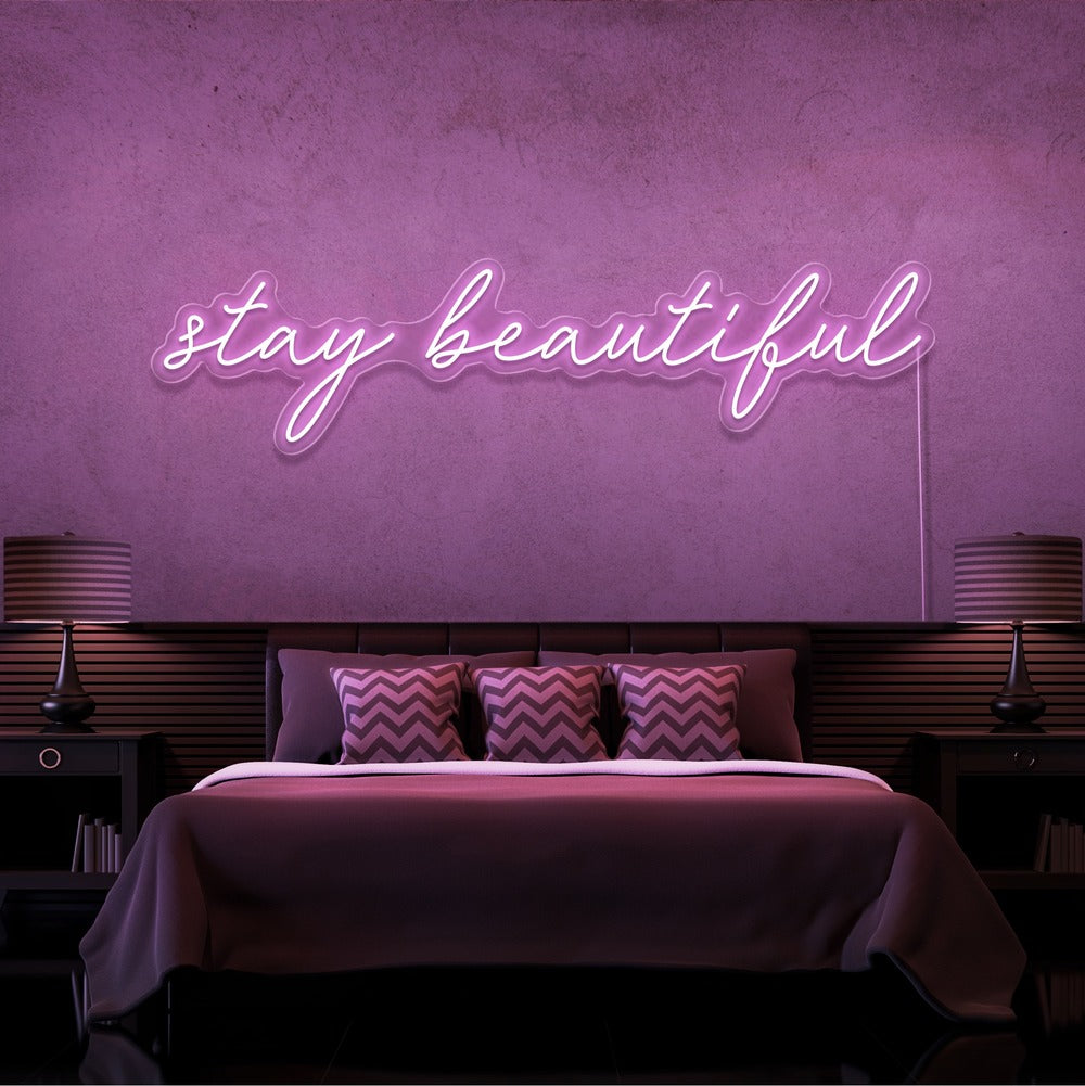 light pink stay beautiful neon sign hanging on bedroom wall