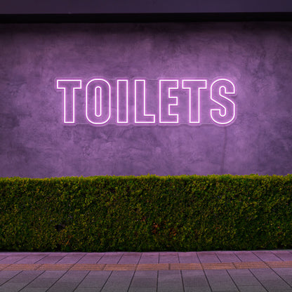 light pink toilets neon sign hanging on outdoor wall