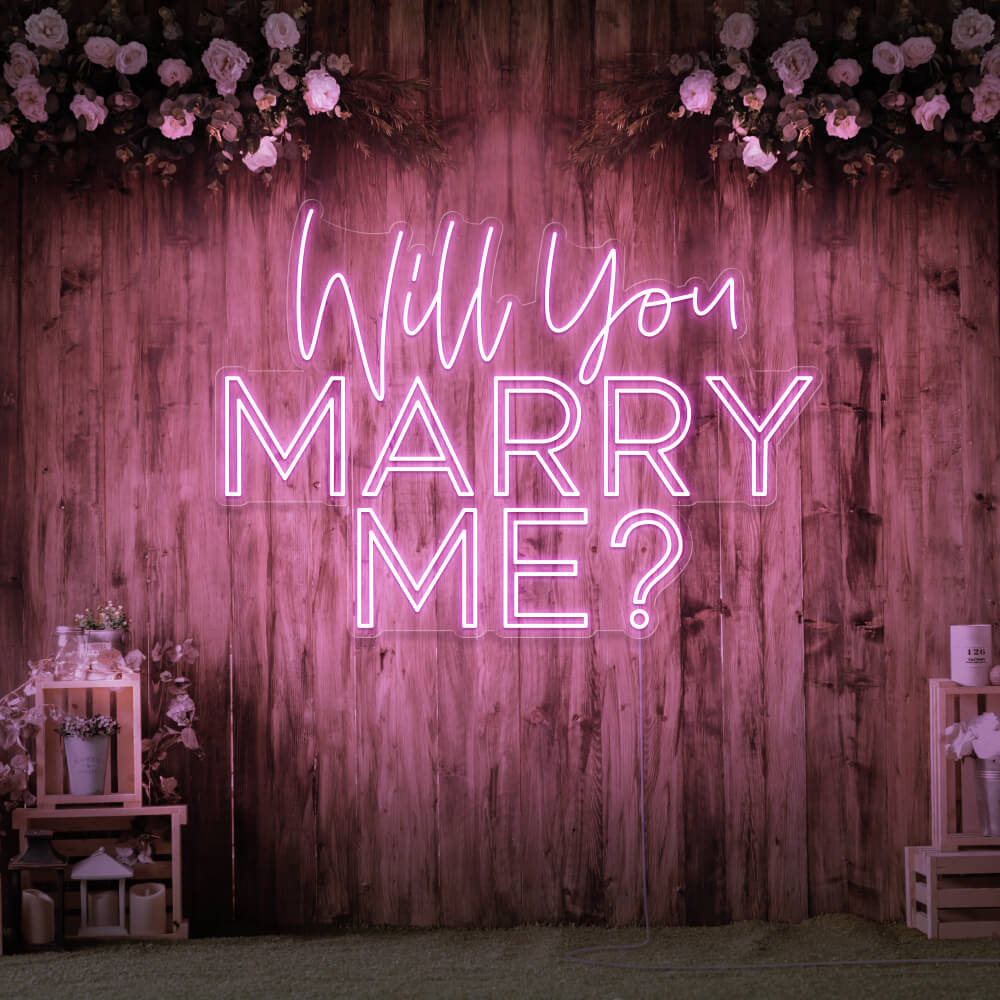 light pink will you marry me neon sign hanging on timber wall