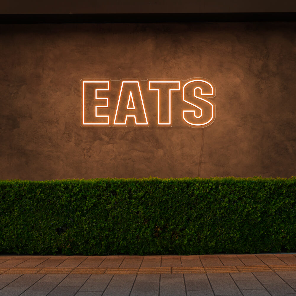 orange eats neon sign hanging on outside wall