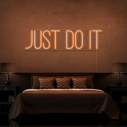 orange just do it neon sign hanging on bedroom wall