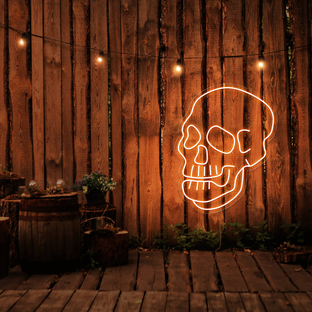 orange skull neon sign hanging on timber fence