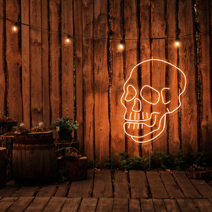 orange skull neon sign hanging on timber fence