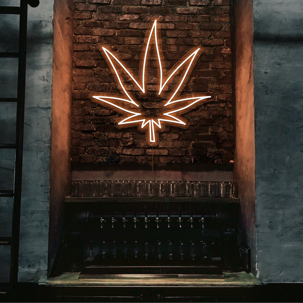 orange weed leaf neon sign hanging on bar wall