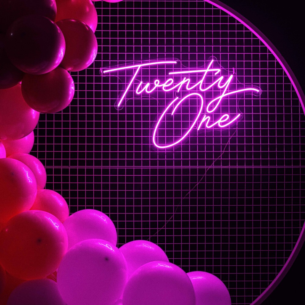 hot pink twenty one neon sign hanging on white mesh backdrop