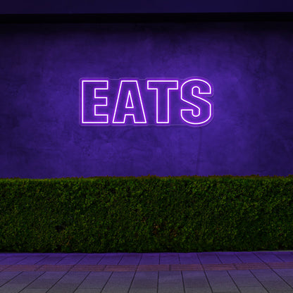 purple eats neon sign hanging on outside wall