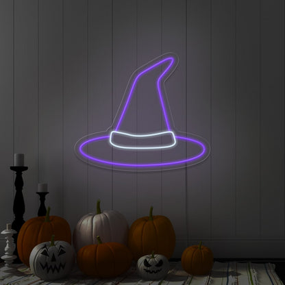 purple witch hat neon sign hanging on wall above pumpkins