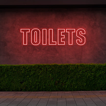 red toilets neon sign hanging on outdoor wall