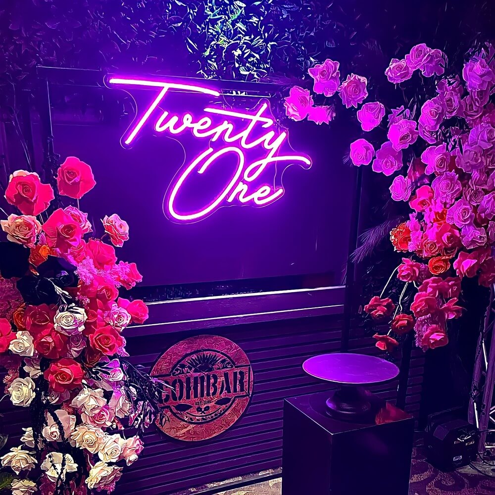 hot pink twenty one neon sign hanging on frame with flowers