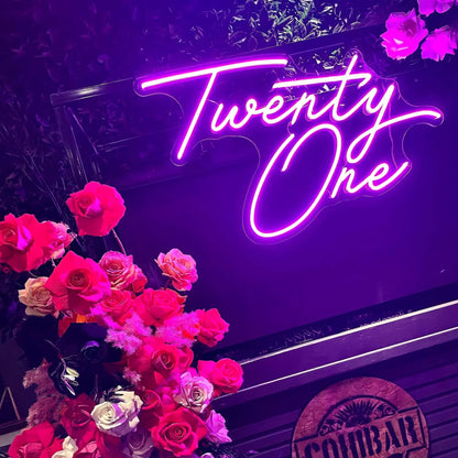 pink twenty one neon sign hanging on black frame with flowers