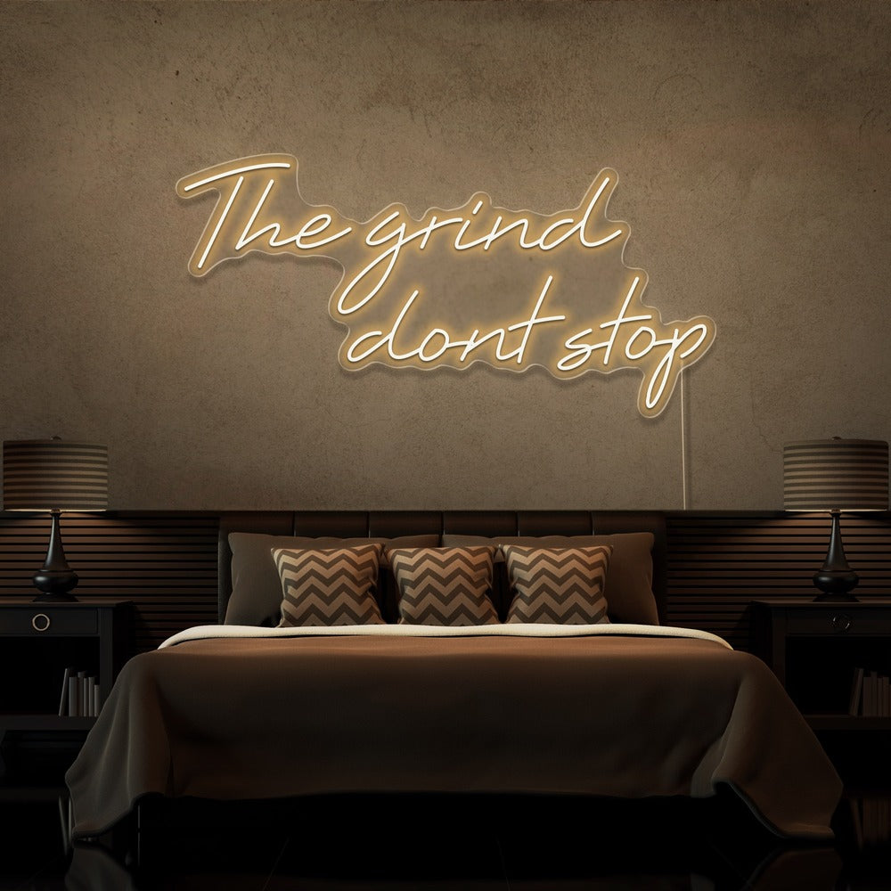 warm white the grind dont stop neon sign hanging on bedroom wall