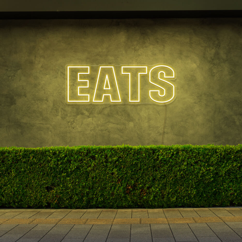 yellow eats neon sign hanging on outside wall