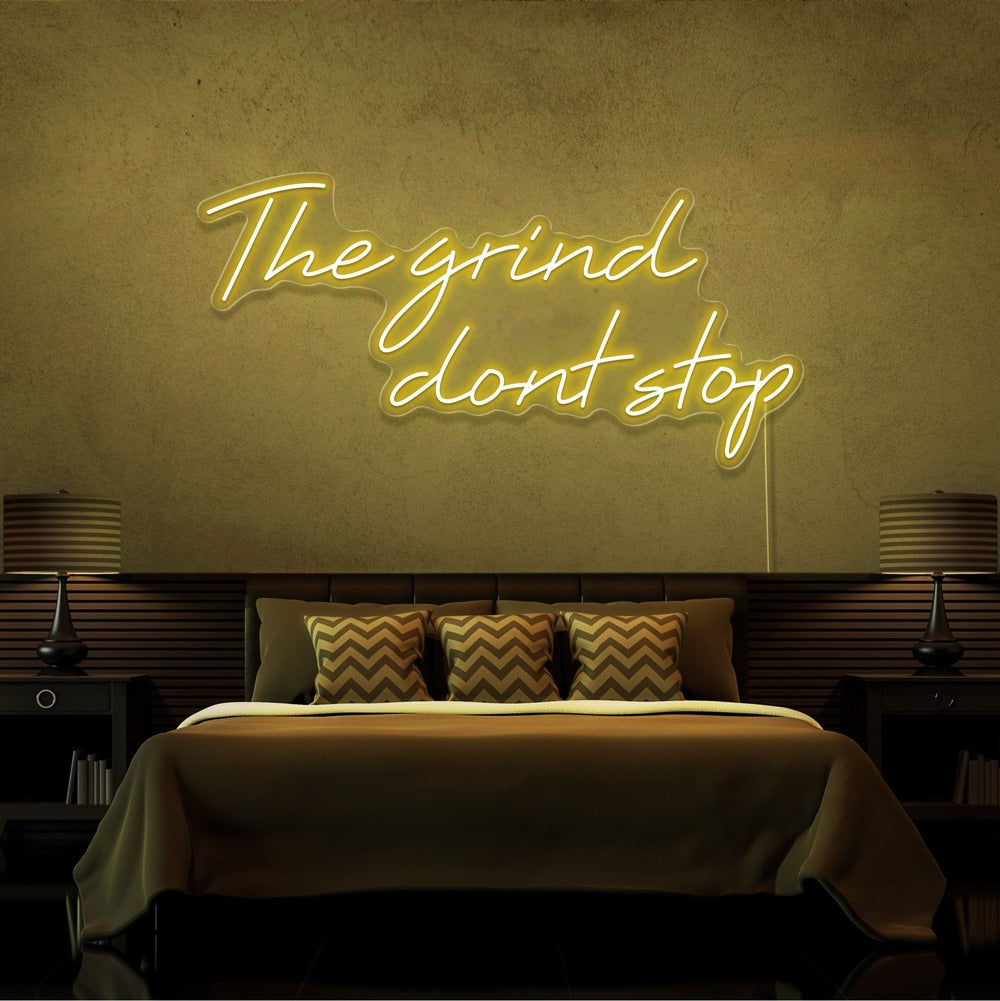 yellow the grind dont stop neon sign hanging on bedroom wall