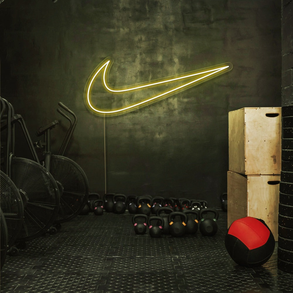 yellow nike swoosh neon sign hanging on gym wall