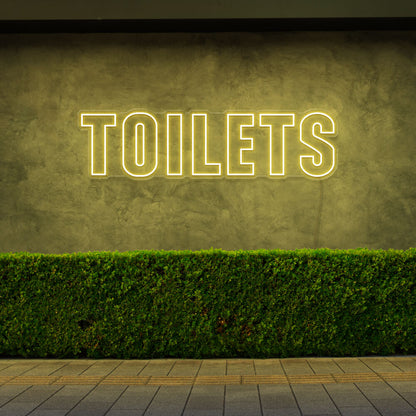 yellow toilets neon sign hanging on outdoor wall